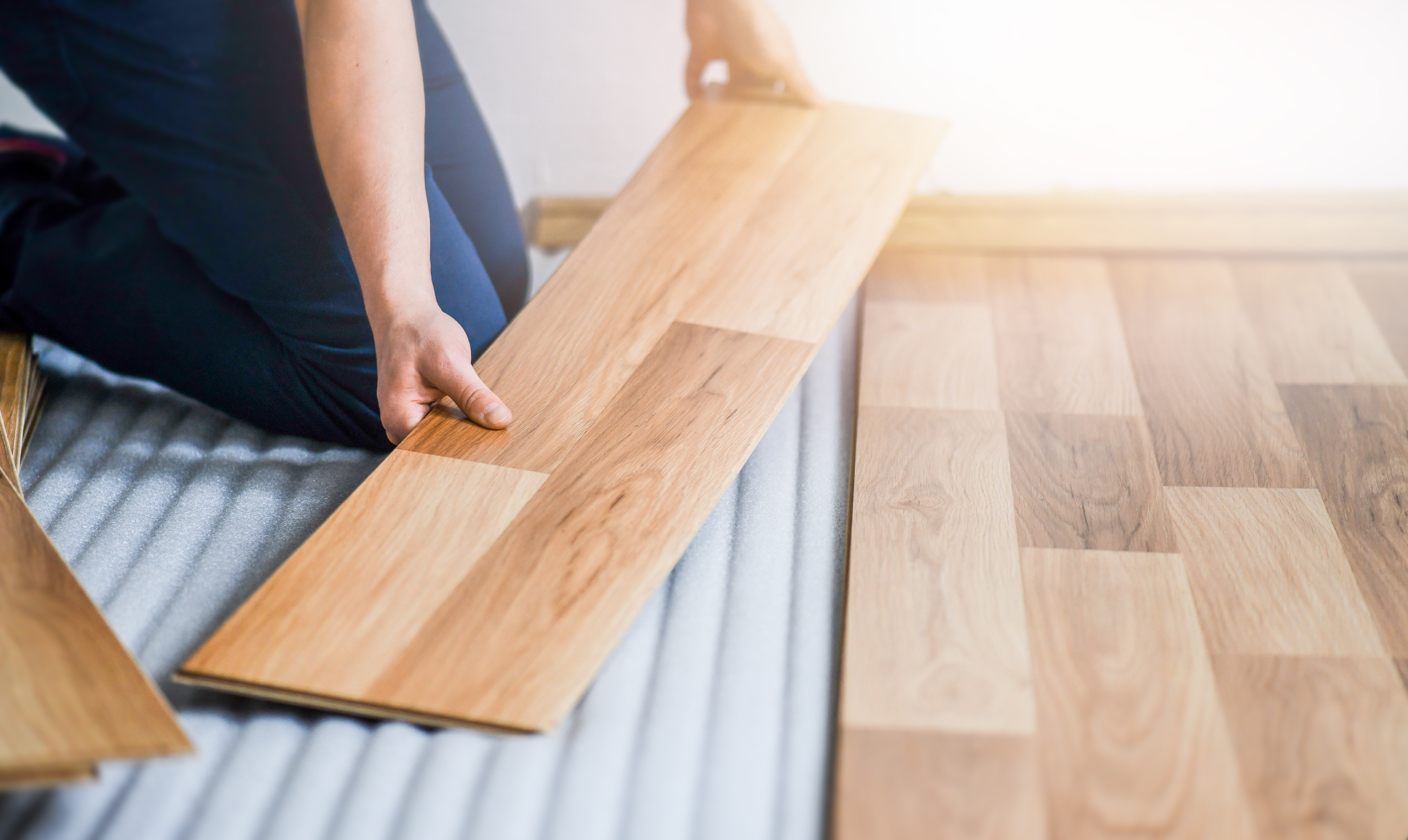 Worker hands installing timber laminate floor. Wooden floors hou